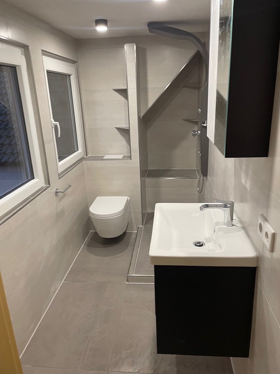 Fertig gefliestes Badezimmer mit bodengleicher Dusche und Waschtisch – Fliesenleger Alzenau
